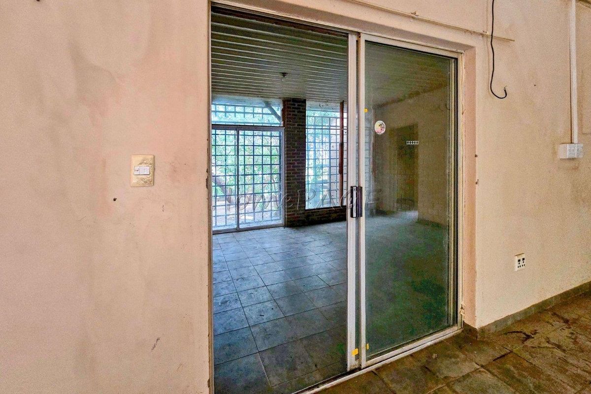 An interior view showing a sliding glass door leading to a tiled patio area with brick accents and security bars.