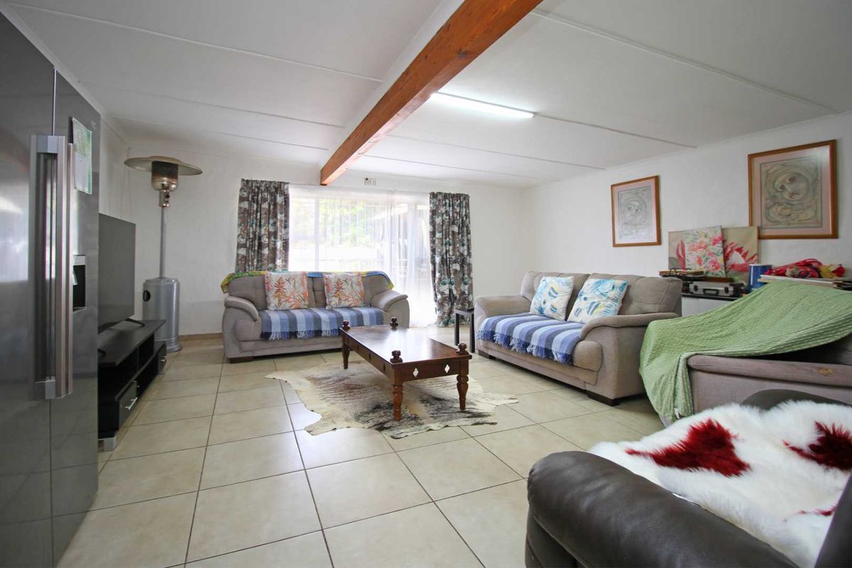 Spacious living area featuring tiled flooring and a prominent exposed timber ceiling beam, providing a functional and open layout.