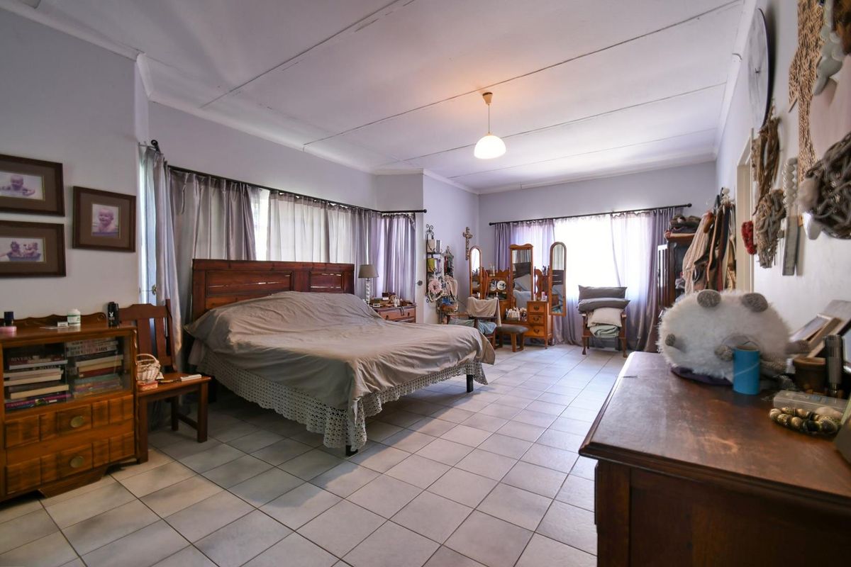 Spacious bedroom featuring tiled flooring and large windows with curtain treatments, offering a functional layout with ample natural light.