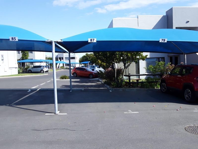 Outdoor parking area featuring designated bays with blue shade cloth carports for vehicle protection.