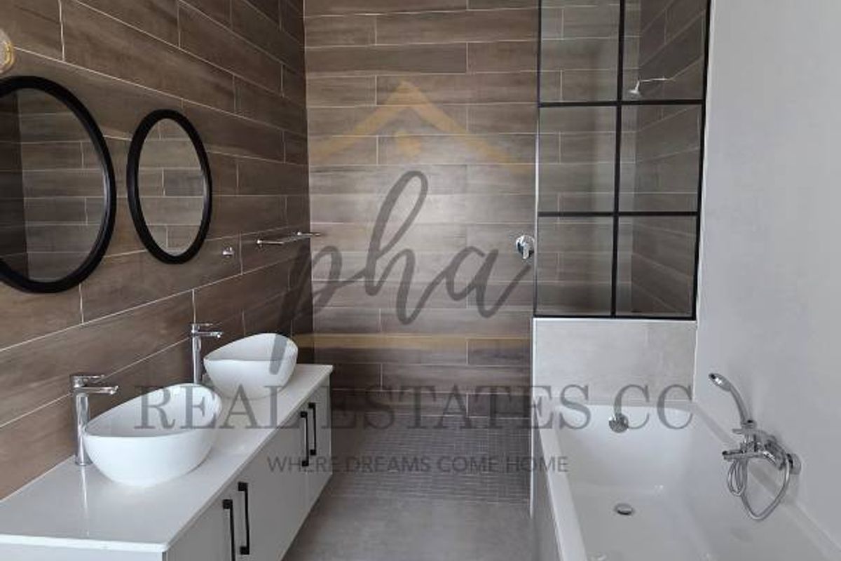 Modern bathroom featuring a double vanity with vessel sinks, a sleek freestanding bathtub, and a stylish glass-panelled shower screen with wood-look tiled feature walls.