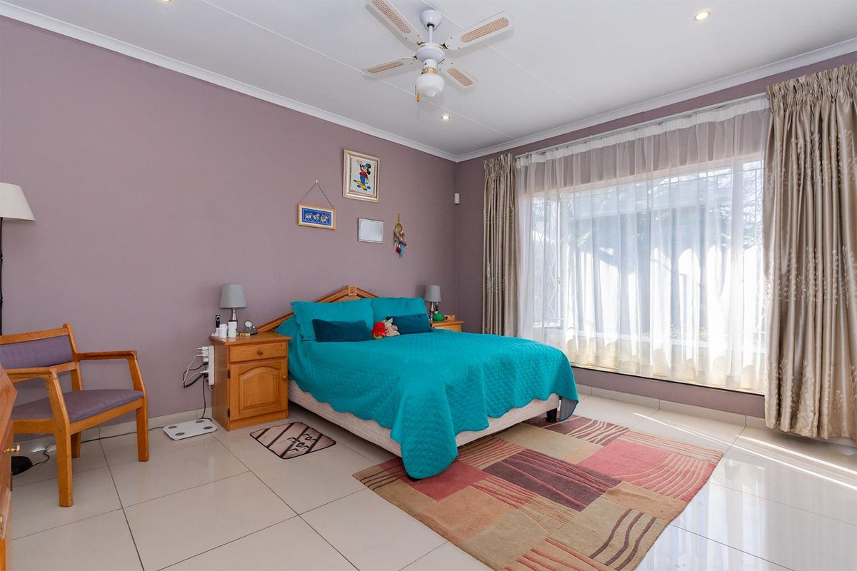A spacious bedroom featuring tiled flooring, recessed lighting, and a ceiling fan, with large windows providing ample natural light.