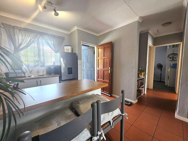 Open plan kitchen area featuring a breakfast bar, tiled flooring, and direct access to an exterior door, connecting to the hallway.