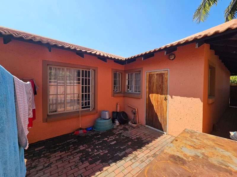 Rear exterior courtyard featuring brick paving, terracotta roof tiles, and secure window bars, providing a functional outdoor utility space.