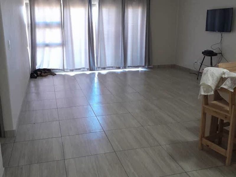 Spacious living area featuring neutral tiled flooring and large sliding glass doors that provide ample natural light.