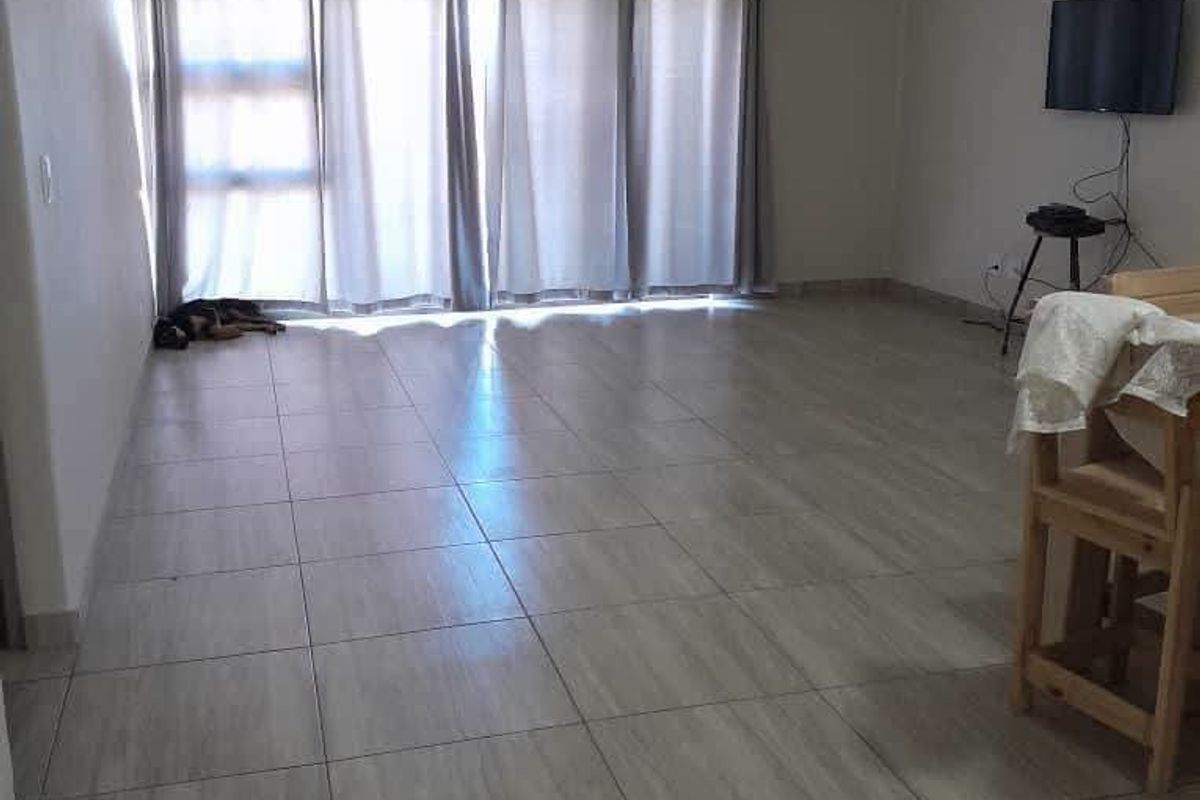 Spacious living area featuring neutral tiled flooring and large sliding glass doors that provide ample natural light.