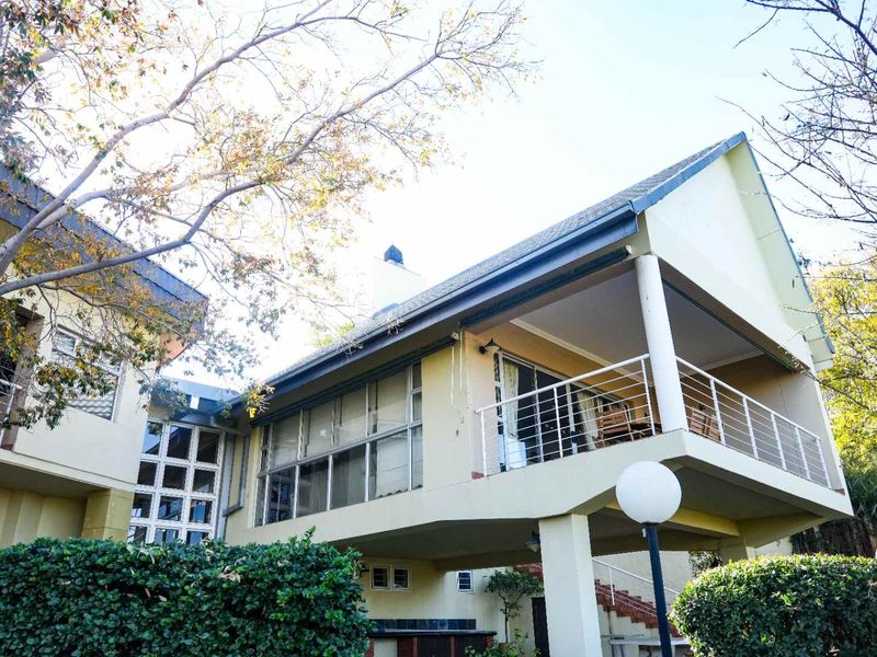 Rear view of the property featuring a raised balcony with metal railings, sliding glass doors, and a pitched tiled roof.