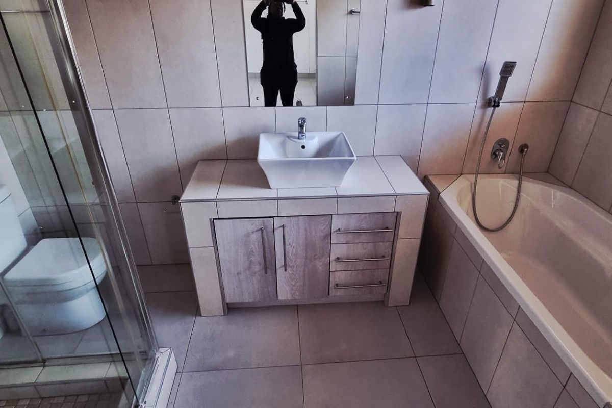 Modern bathroom featuring a tiled shower enclosure, a built-in vanity with a vessel sink, and a separate bathtub with wall-mounted fixtures.