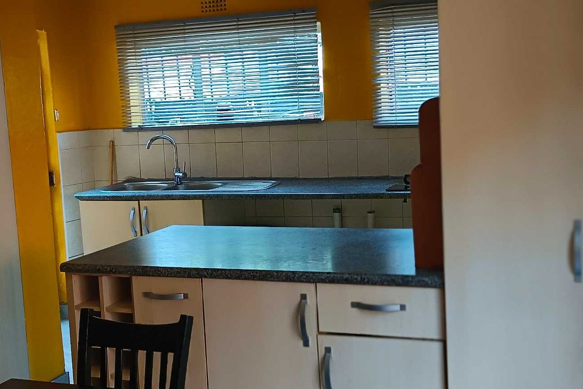 A functional kitchen featuring laminate countertops, double sink with mixer tap, and built-in cabinetry, offering a practical layout for daily meal preparation.