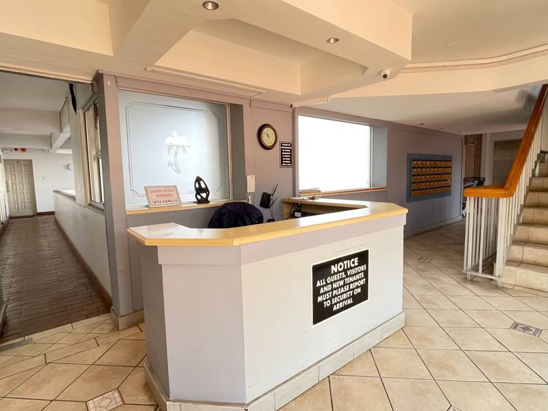Apartment building entrance lobby featuring a reception desk, mailboxes, and a staircase leading to upper levels.