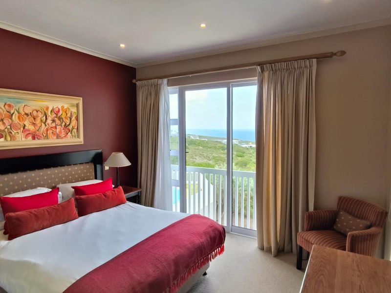 A well-maintained bedroom featuring a sliding glass door that opens to a balcony with scenic coastal views and recessed ceiling lighting.