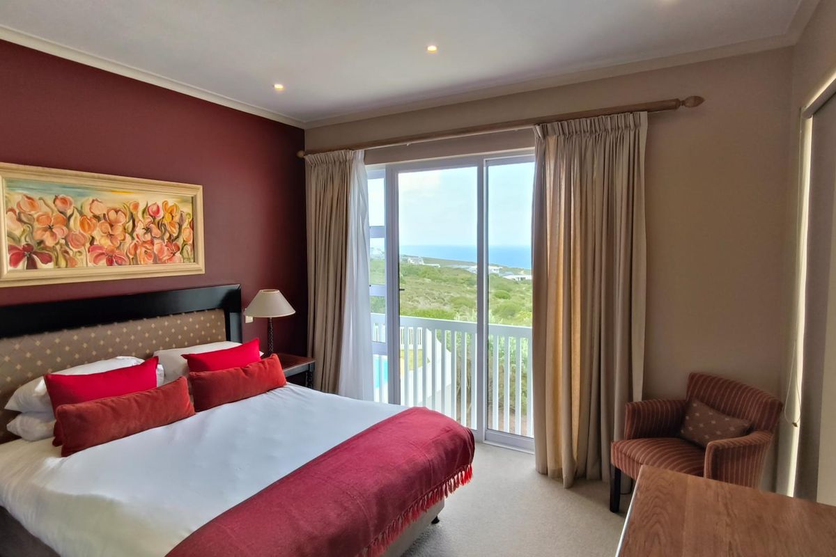 A well-maintained bedroom featuring a sliding glass door that opens to a balcony with scenic coastal views and recessed ceiling lighting.