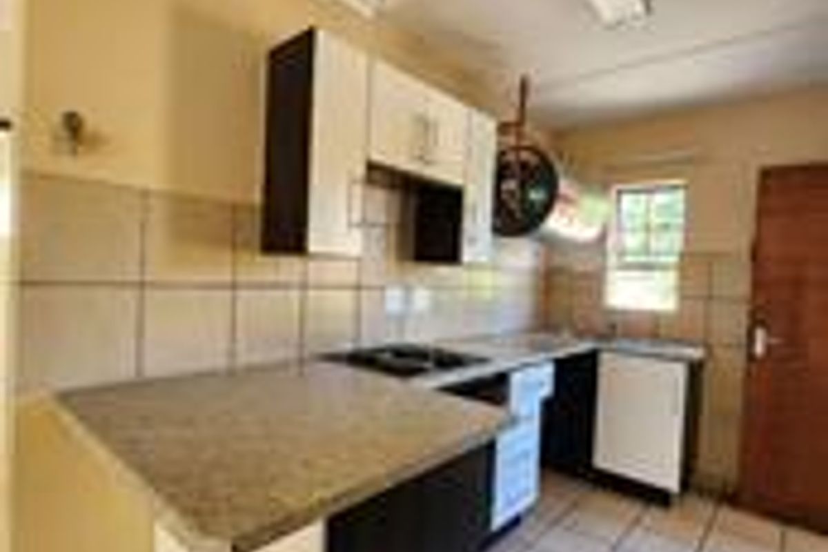 A functional kitchen featuring laminate countertops, built-in cabinetry, and ceramic tile flooring, offering a clean and practical layout for daily use.