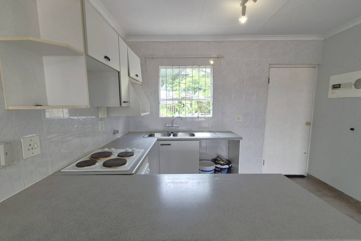 A functional kitchen featuring built-in cabinetry, a double sink, a four-plate electric hob, and tiled splashbacks with a breakfast counter.
