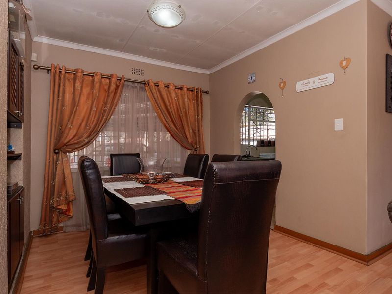 A dining room featuring laminate flooring and an arched doorway leading to the kitchen area.