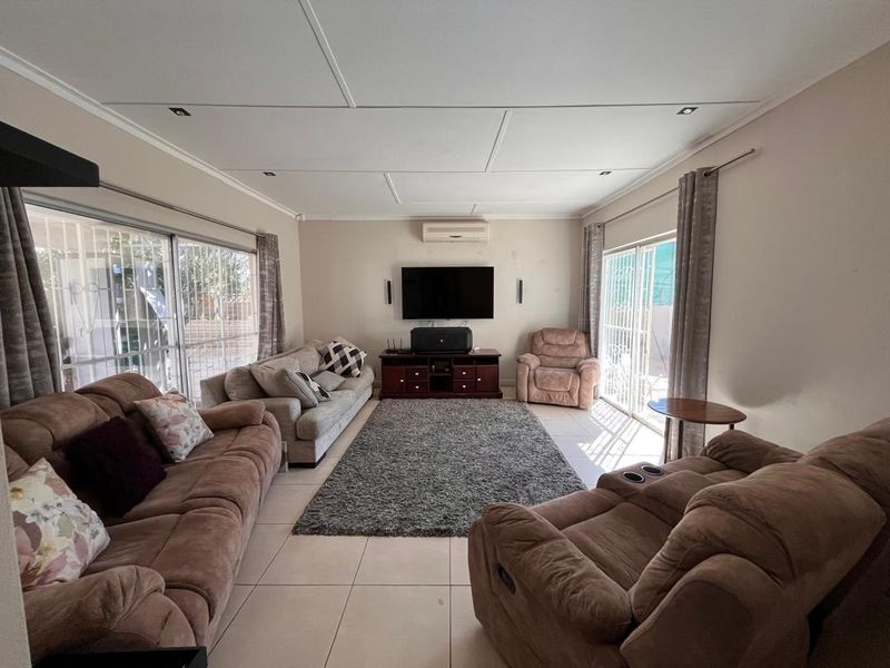Spacious living room featuring tiled flooring, split-system air conditioning, and dual sliding glass doors providing access to the exterior.