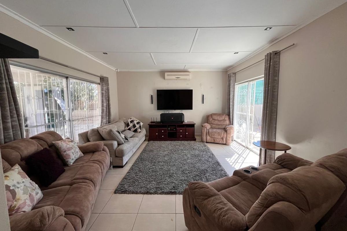 Spacious living room featuring tiled flooring, split-system air conditioning, and dual sliding glass doors providing access to the exterior.