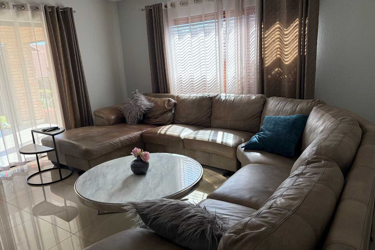 A comfortable living room featuring large sliding glass doors that provide natural light and access to the outdoor area, complemented by neutral tiled flooring.