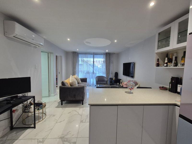 Modern open-plan living area featuring marble-look tiled flooring, recessed lighting, a split-system air conditioner, and a functional kitchen island with stone countertops.