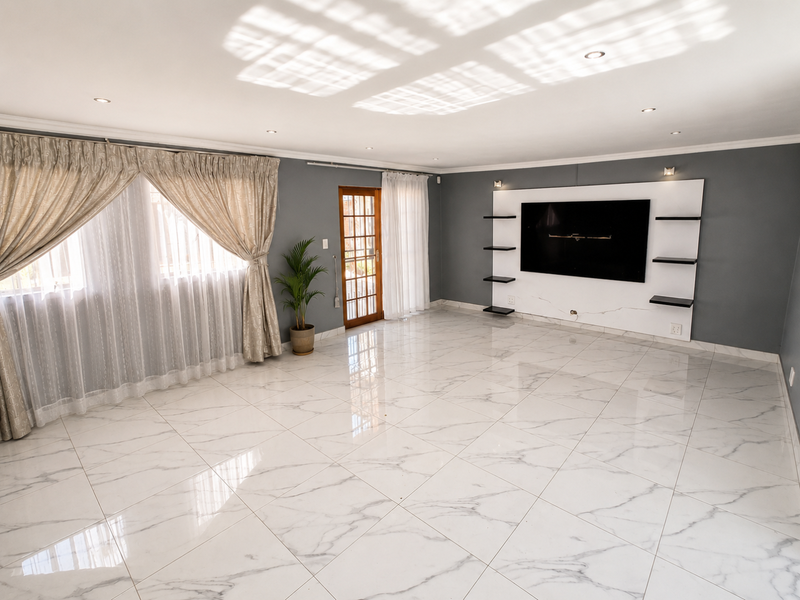 Spacious living room featuring polished marble-look floor tiles, a modern built-in media wall, recessed lighting, and direct access to the exterior via a timber-framed door.