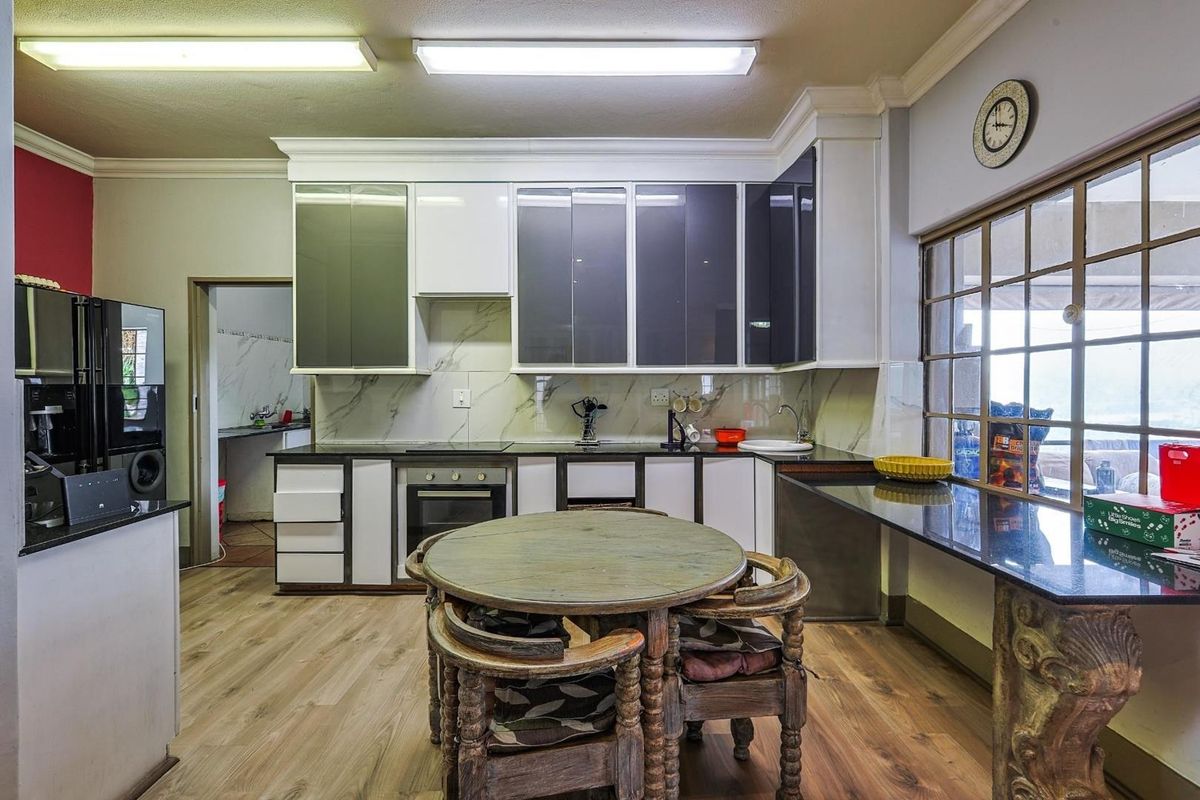 A functional kitchen featuring modern two-tone cabinetry, marble-look splashbacks, integrated oven, and a breakfast counter with views.