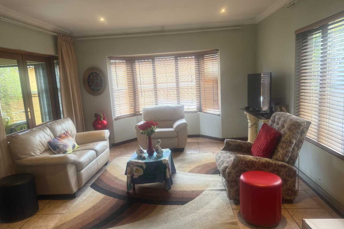 A comfortable living room featuring tiled flooring, a prominent bay window with timber blinds, and recessed downlighting, providing a bright and functional space.