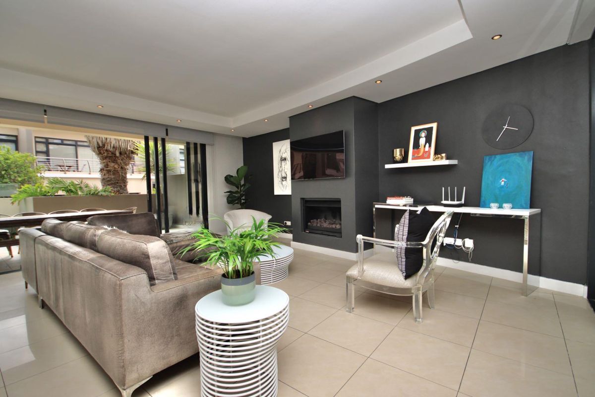 Modern living room featuring a built-in fireplace, recessed ceiling lighting, and large sliding glass doors opening to an outdoor patio area.