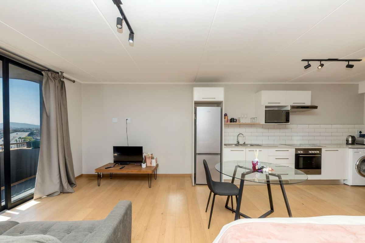 Modern open-plan living area featuring a well-equipped kitchen with subway tile backsplash, integrated appliances, and direct access to a balcony with scenic views.