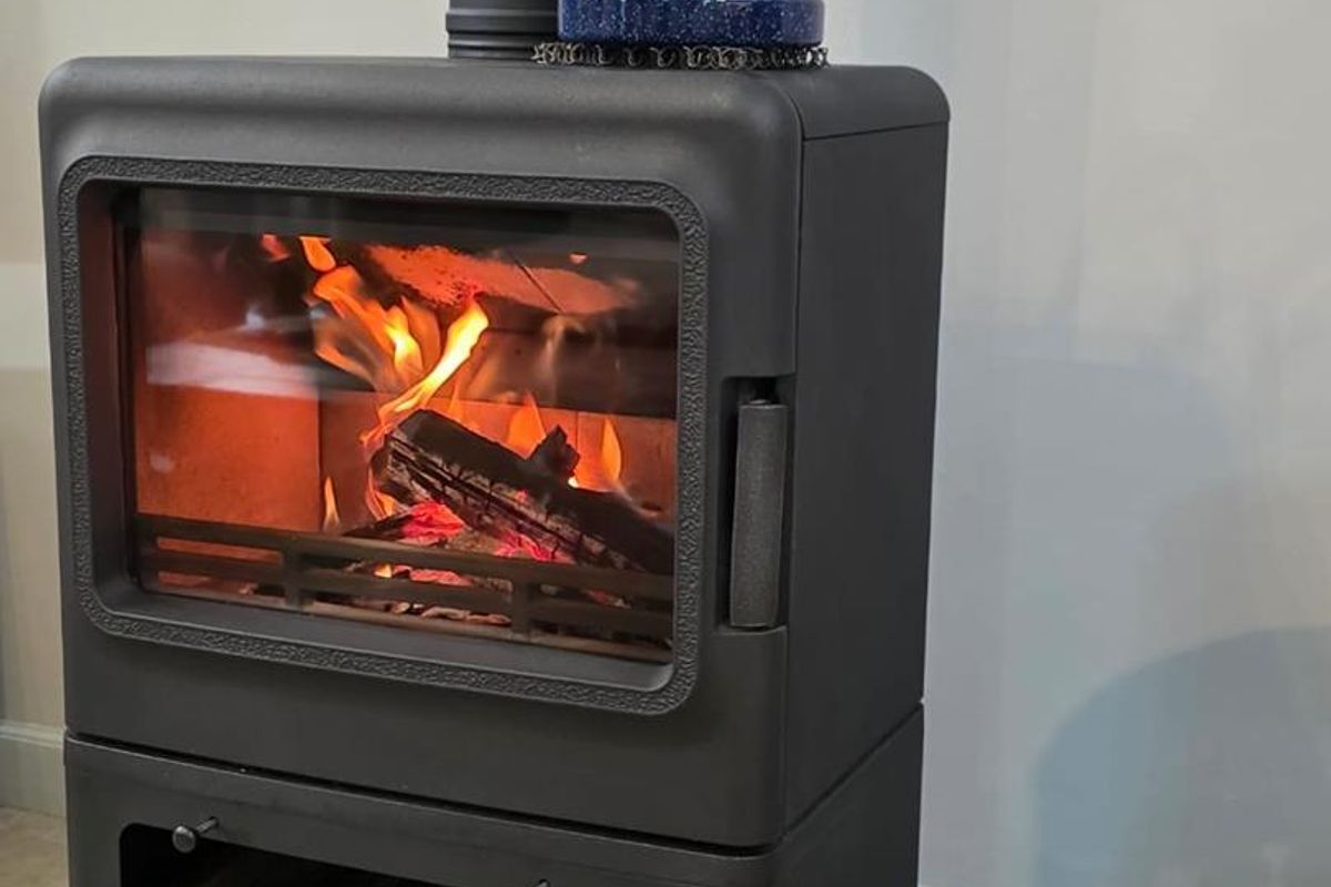 A modern freestanding wood-burning fireplace with a built-in log storage compartment, providing efficient heating and a cozy focal point for the living area.