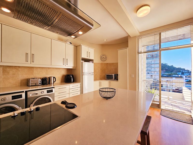 Modern kitchen featuring stone countertops, built-in cabinetry, integrated appliances, and a seamless transition to a private balcony with urban views.