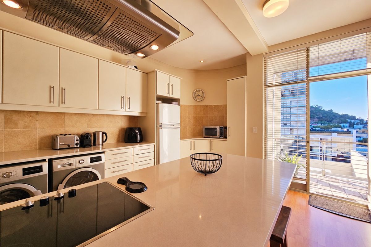 Modern kitchen featuring stone countertops, built-in cabinetry, integrated appliances, and a seamless transition to a private balcony with urban views.