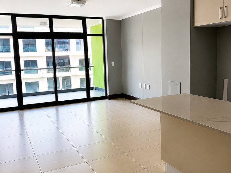 Modern open-plan living area featuring tiled floors, a stone kitchen island, and large sliding glass doors leading to a private balcony.