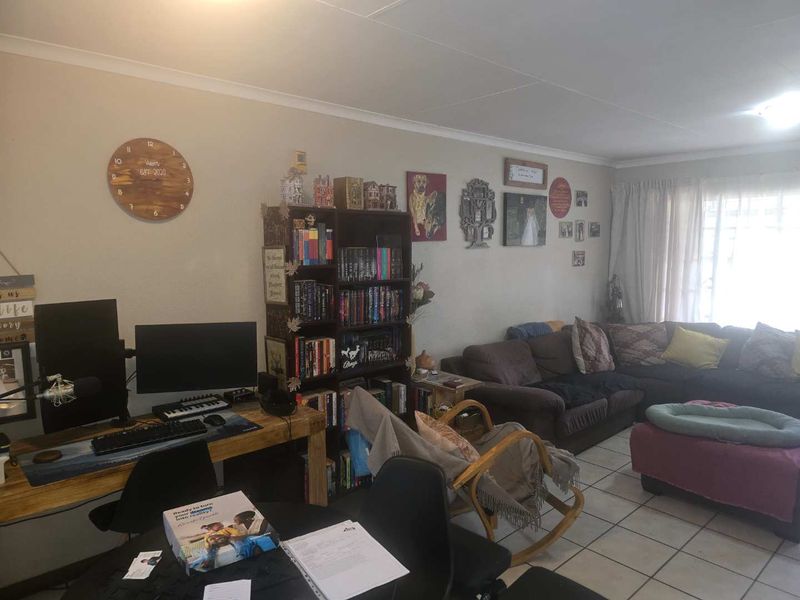 A spacious living area featuring tiled flooring and coved ceilings, offering a versatile layout for relaxation and home office use.