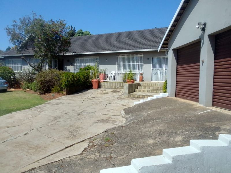 Front exterior view of a single-story house featuring a double garage, concrete driveway, and security bars on windows.