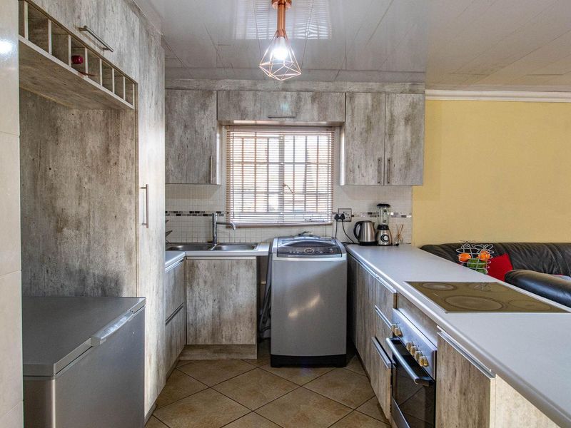 Open-plan kitchen featuring built-in cabinetry, integrated hob and oven, and dedicated laundry space with plumbing connections.