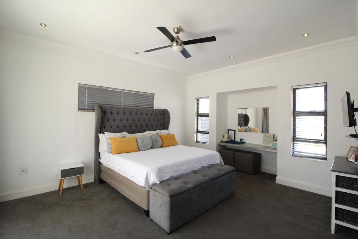 Spacious bedroom featuring recessed vanity area, modern ceiling fan, recessed downlighting, and neutral carpeting.