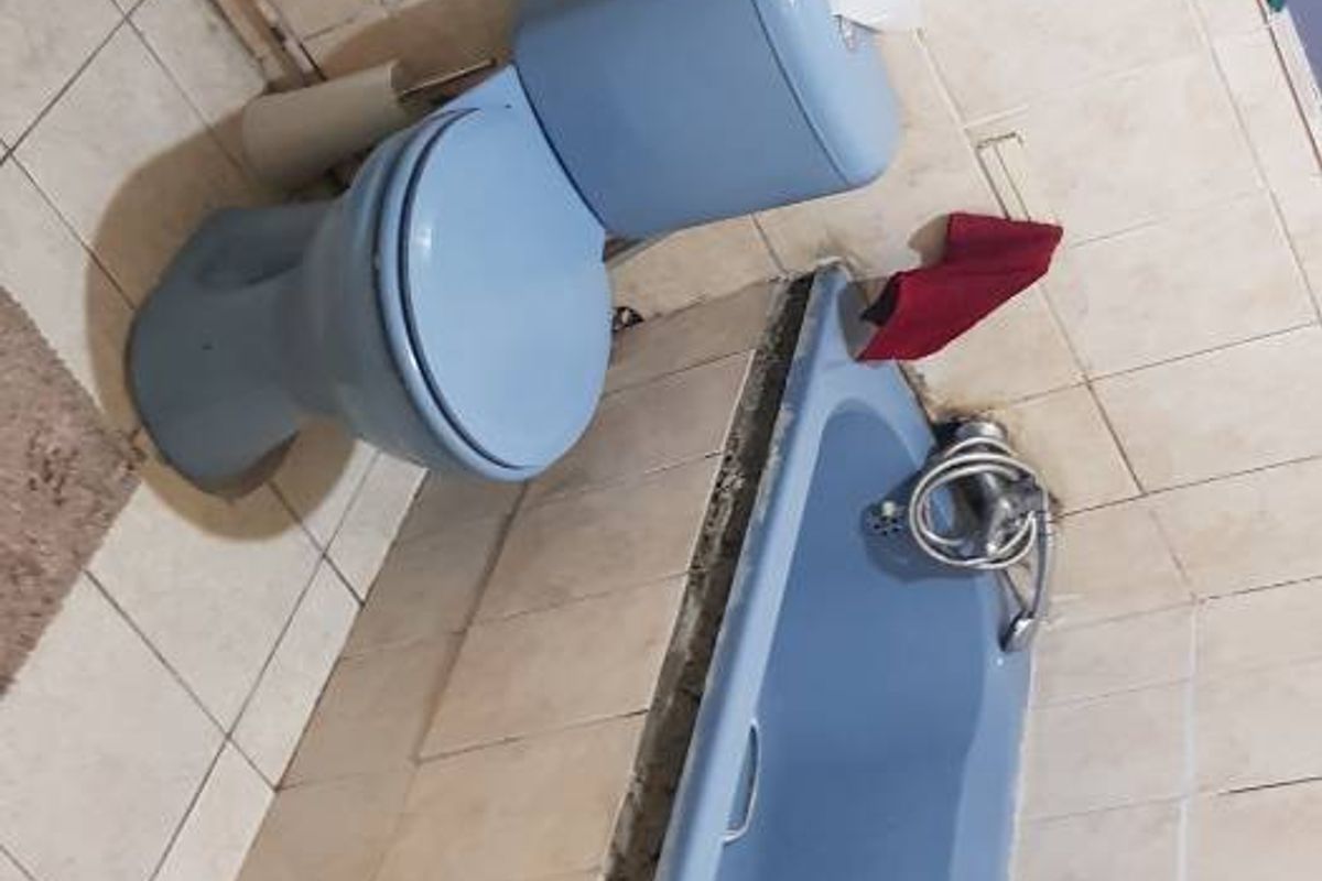 A dated bathroom featuring a blue pedestal basin, matching toilet, and bathtub with tiled walls requiring maintenance and modernization.