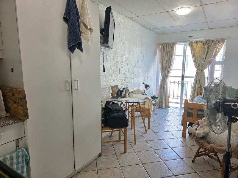 Open-plan living area featuring tiled flooring, a built-in cupboard, and a sliding glass door leading to a balcony.