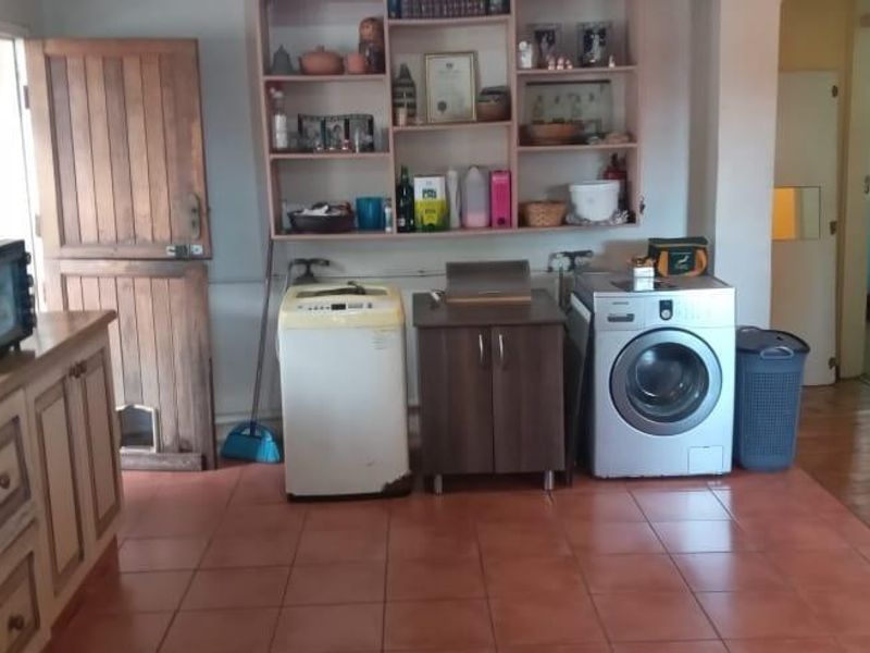 A functional laundry area featuring tiled flooring, built-in shelving, and dedicated plumbing connections for appliances.