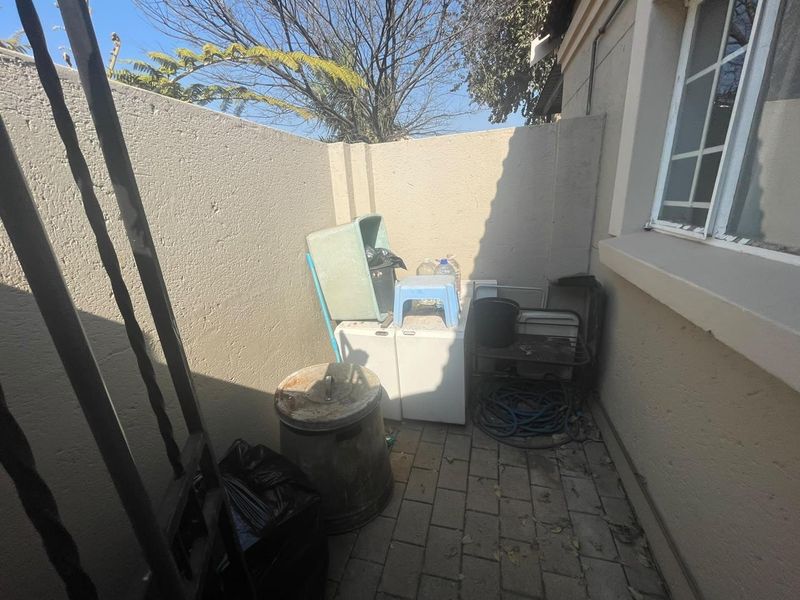 A small, paved outdoor utility area enclosed by boundary walls, suitable for storage or service use.