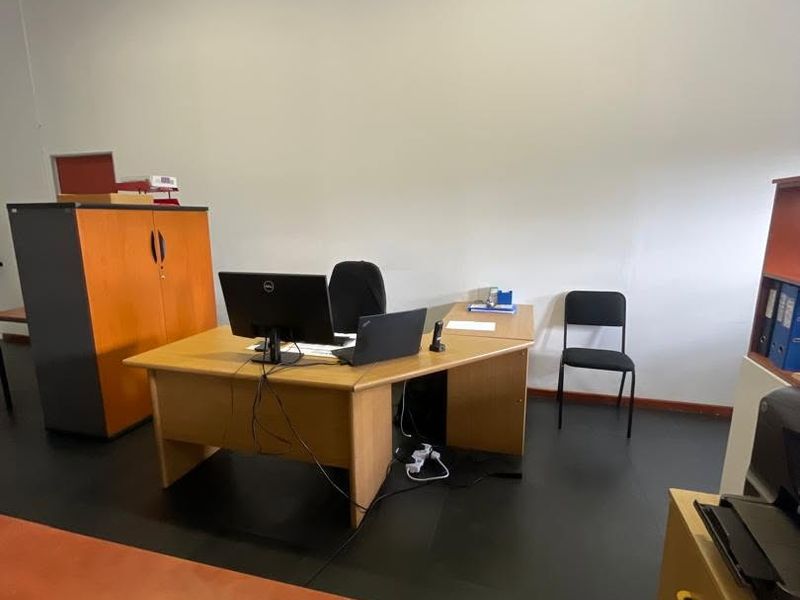 A functional office space featuring dark flooring and neutral walls, suitable for a professional work environment.