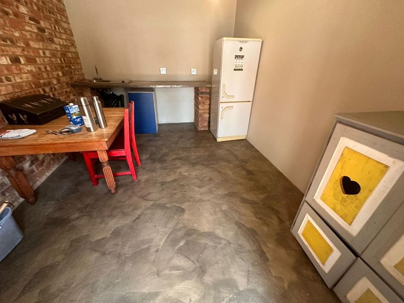 A rustic kitchen area featuring exposed brick walls, a concrete countertop with an integrated sink, and polished concrete flooring.