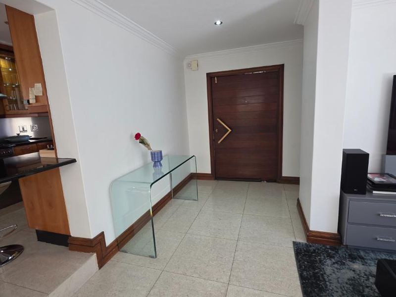 A bright and welcoming entrance area featuring tiled flooring, crown molding, and a solid wood front door, leading into the open-plan living space.
