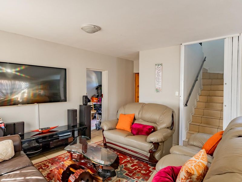 A living room featuring tiled flooring and a staircase with a handrail, providing access to the upper level of the townhouse.