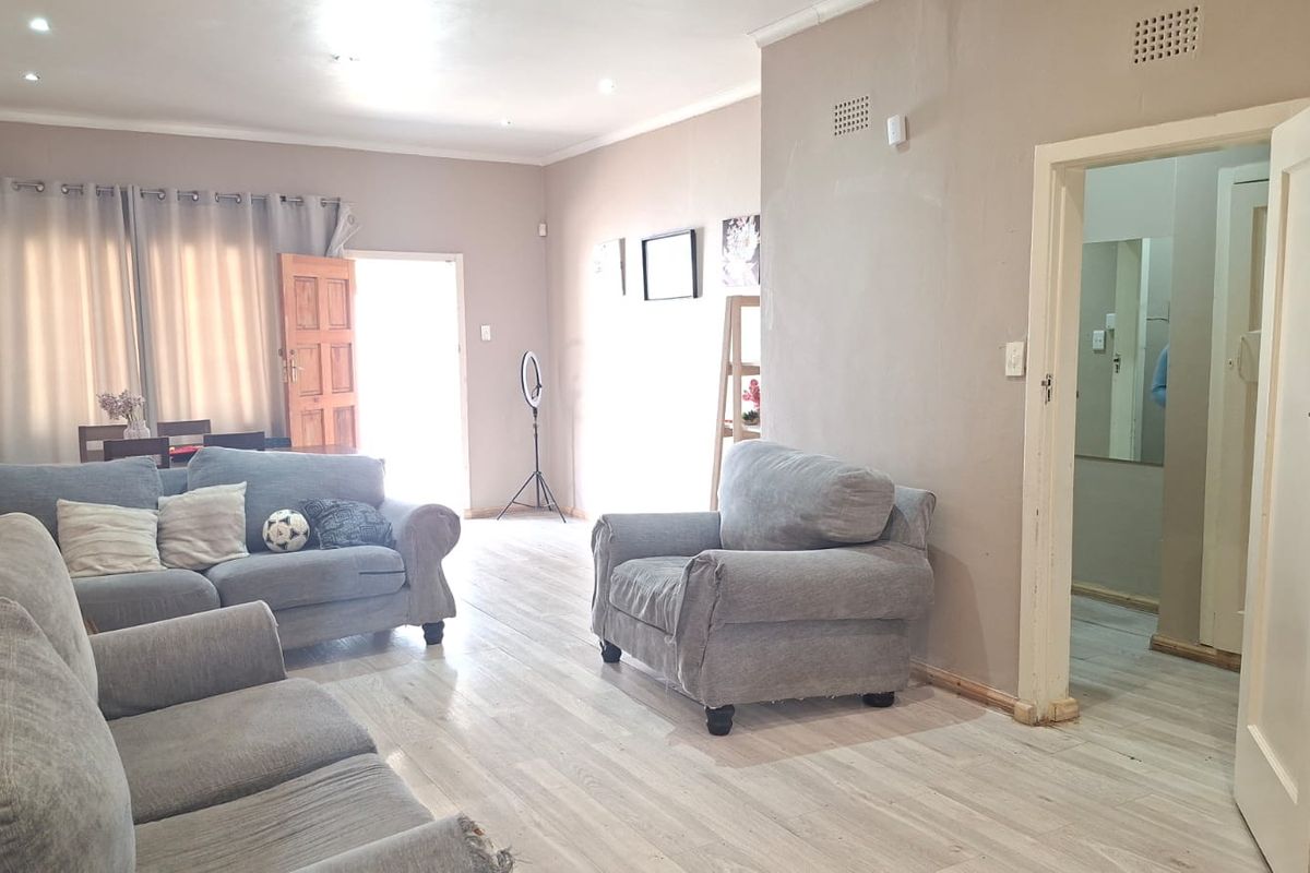 Spacious living room featuring light-toned laminate flooring, recessed downlighting, and neutral wall finishes, providing a versatile area for relaxation.