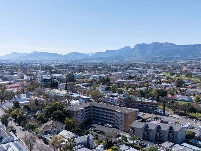 An elevated aerial view showcasing the surrounding urban landscape, neighborhood infrastructure, and distant mountain range.