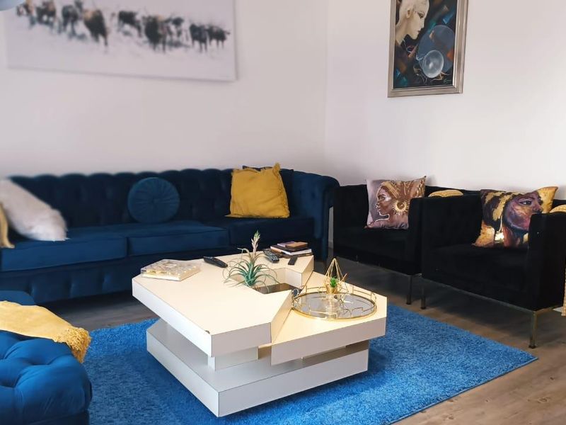 A well-maintained living room featuring neutral walls and modern laminate flooring, providing a comfortable and inviting space for relaxation.