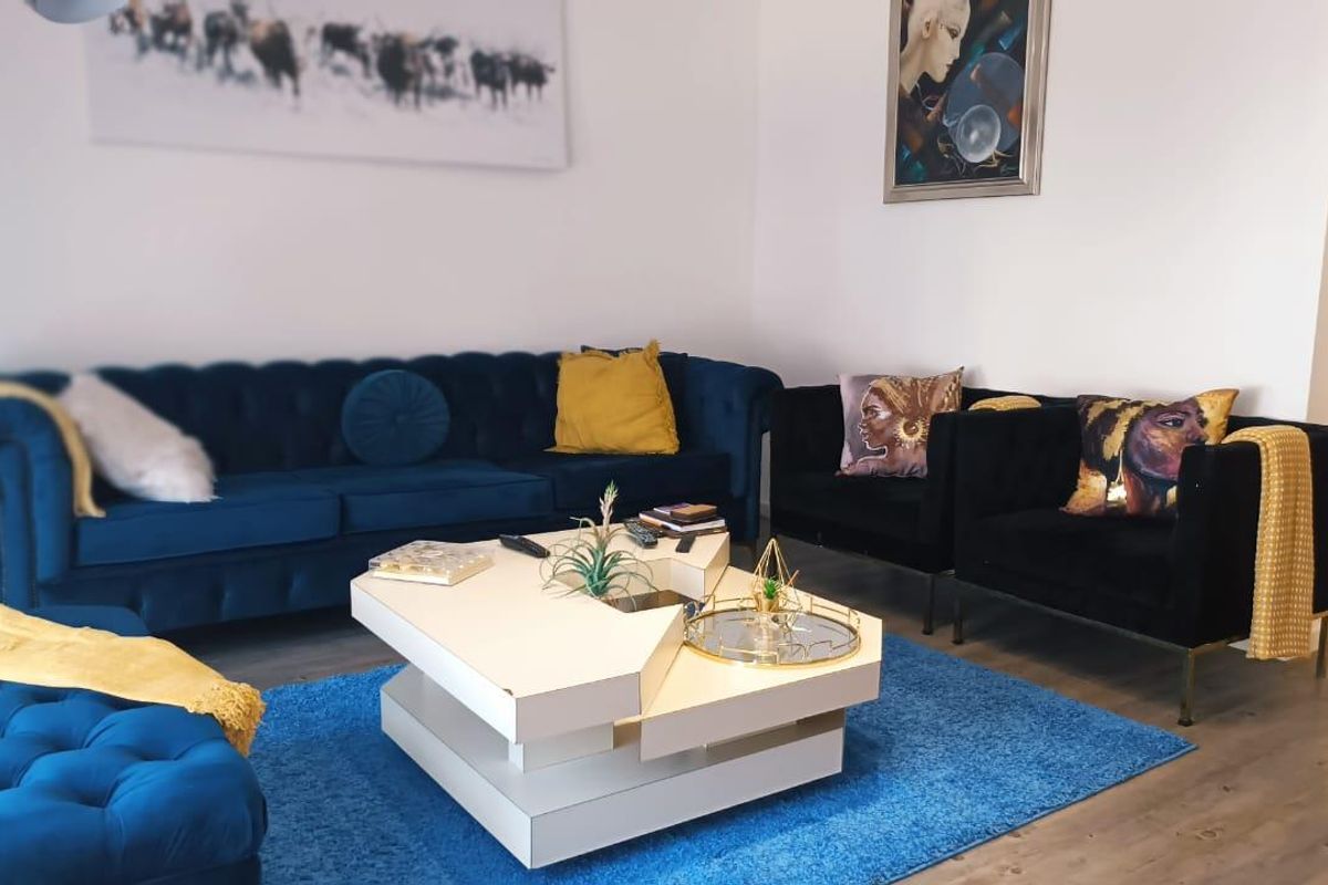 A well-maintained living room featuring neutral walls and modern laminate flooring, providing a comfortable and inviting space for relaxation.