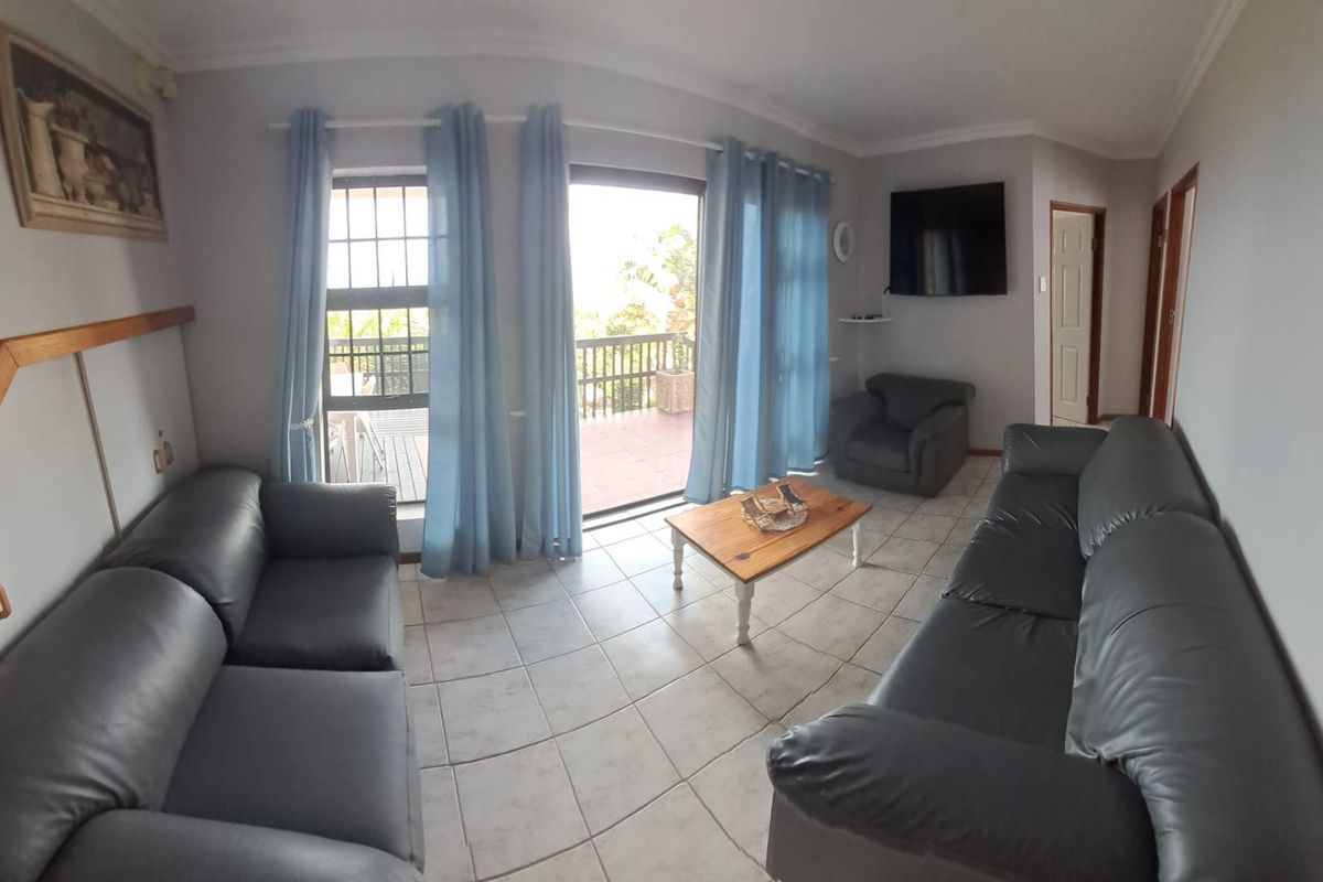 A spacious living room featuring tiled flooring and direct access to an outdoor balcony through large sliding glass doors.