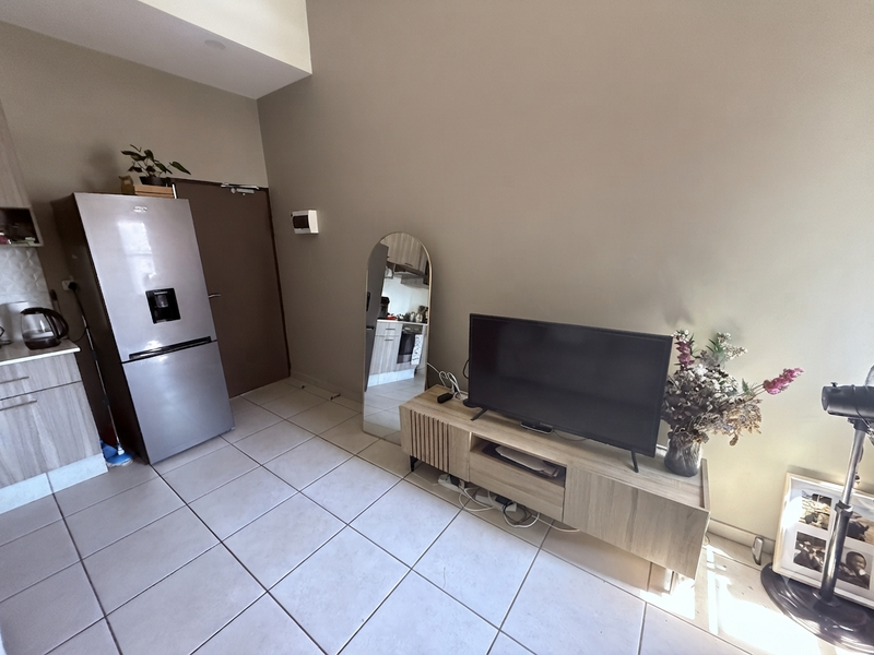 Open plan living area featuring tiled flooring and integrated kitchen cabinetry, providing a functional and versatile space for daily living.
